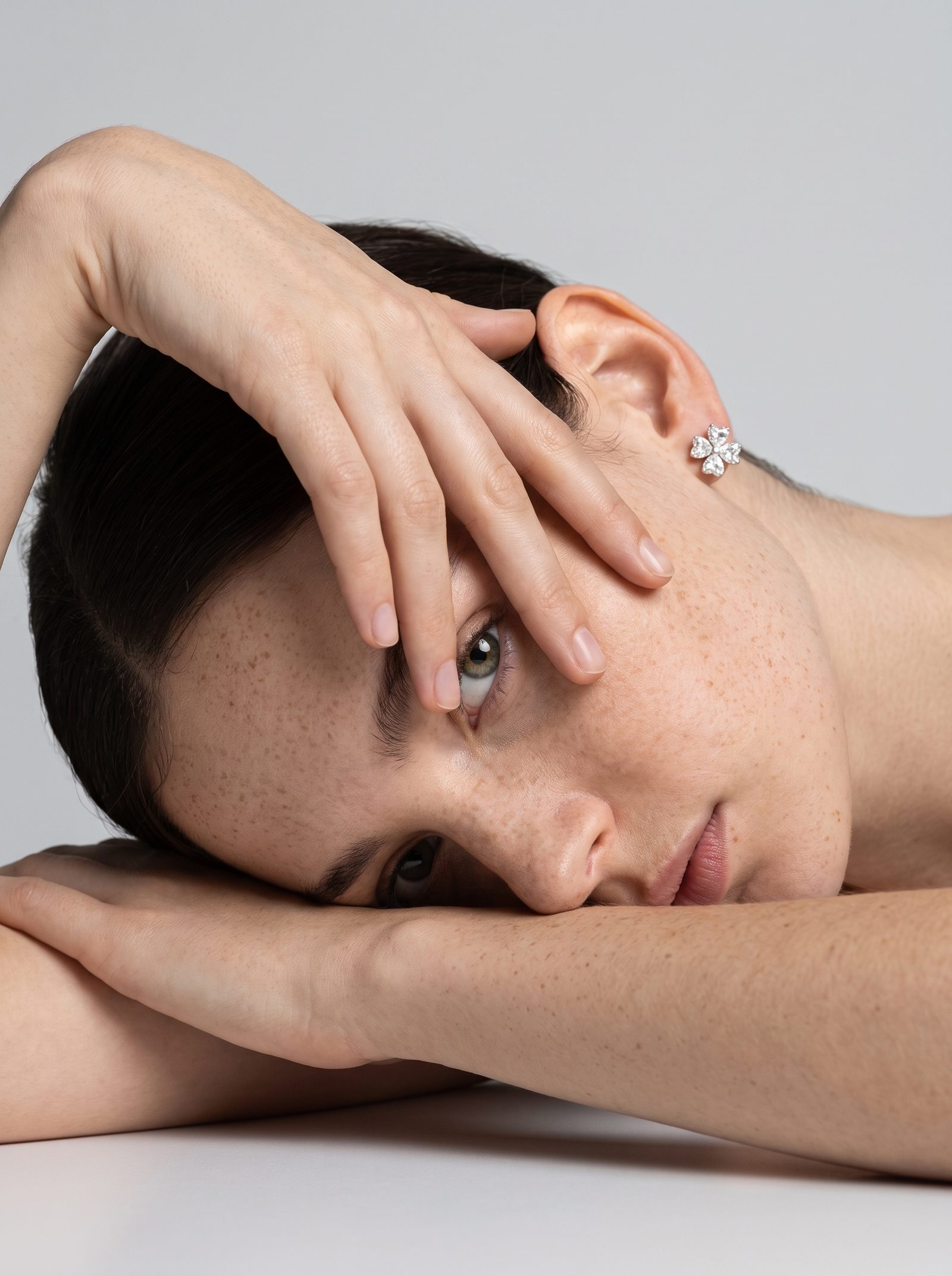 Close portrait of a model wearing a five-petal diamond flower stud earring in white gold